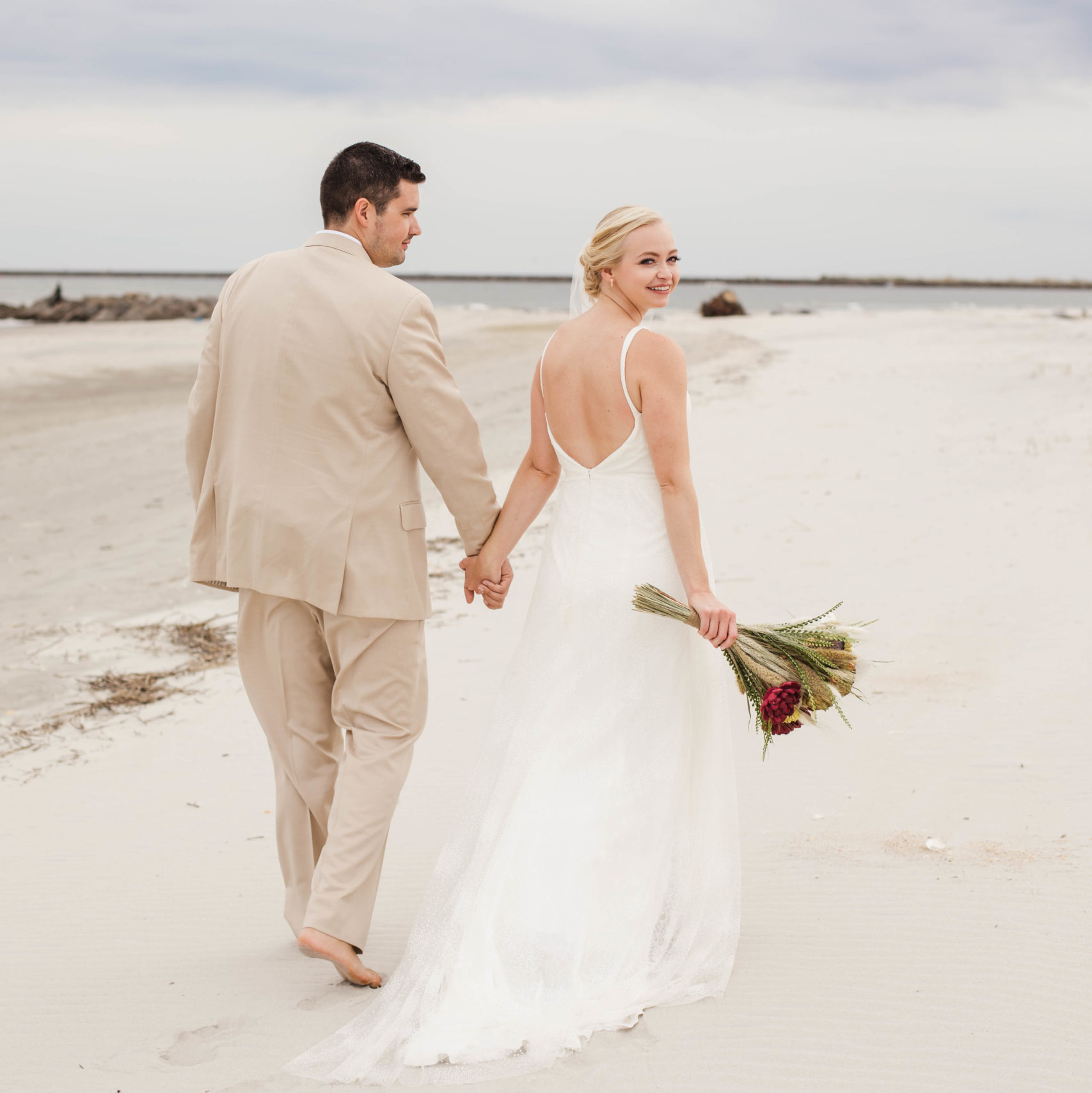 bride and groom walking on beach together after elopement