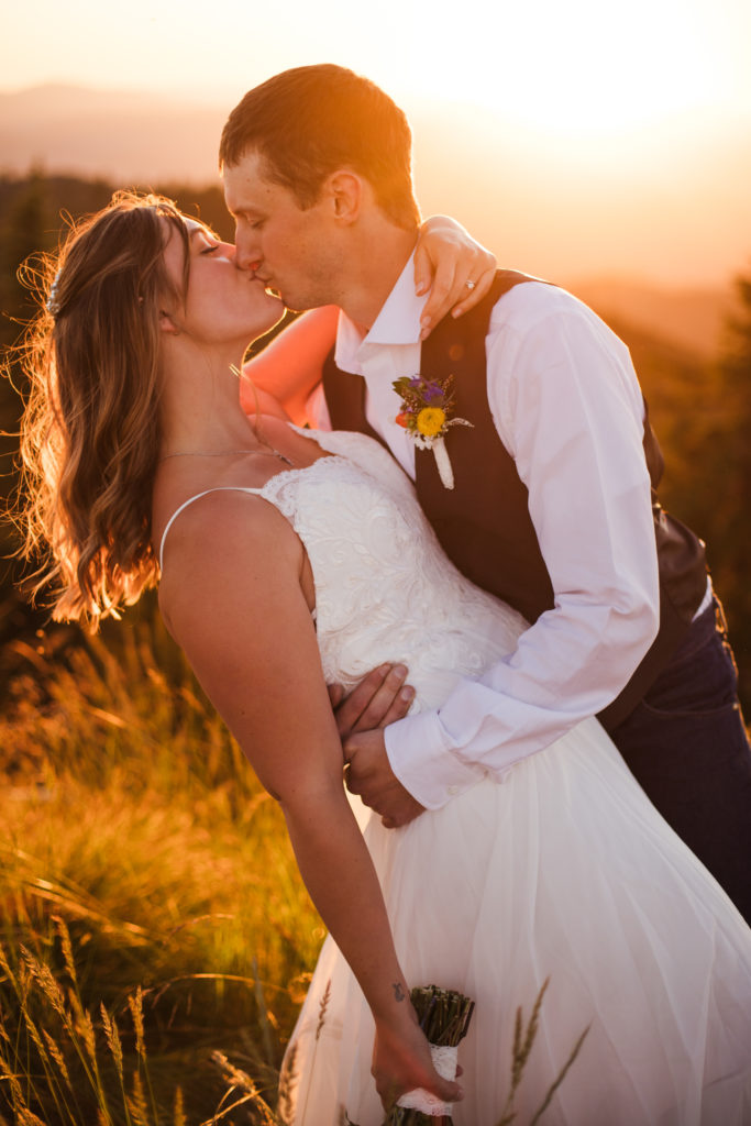 groom holding bride and kissing her during sunset bridals
