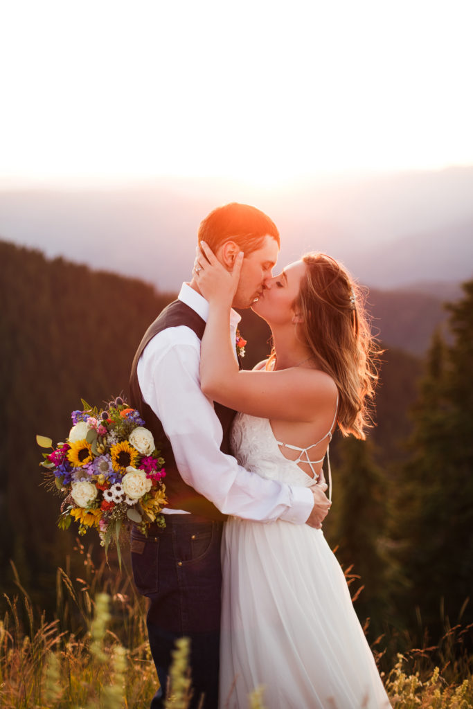 bride and groom hugging and kissing at sunset