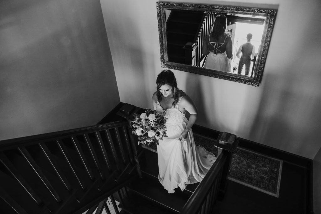 bride wearing lacy wedding gown walking down stairs to elopement