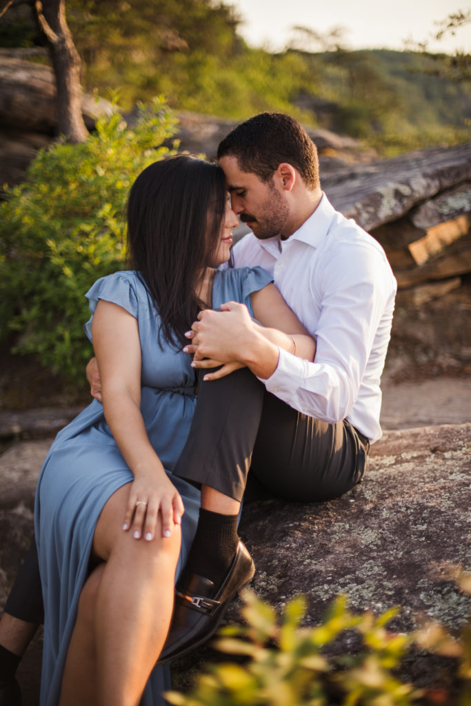 man and woman sitting on rock embracing during fall creek falls engagement session