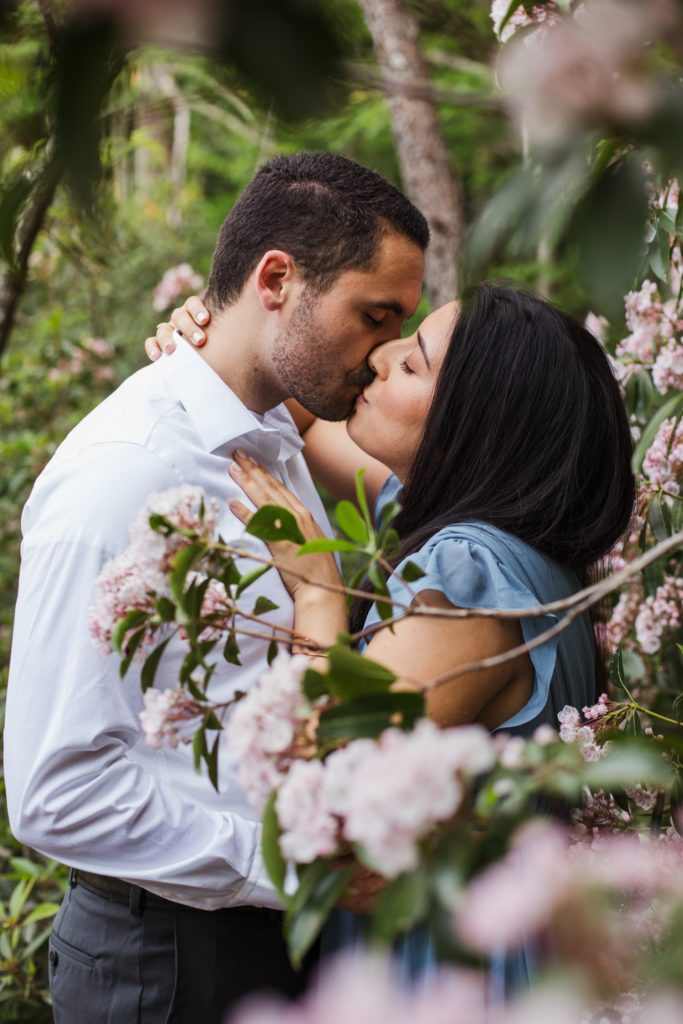 man and woman kissing in blossoms during engagement session