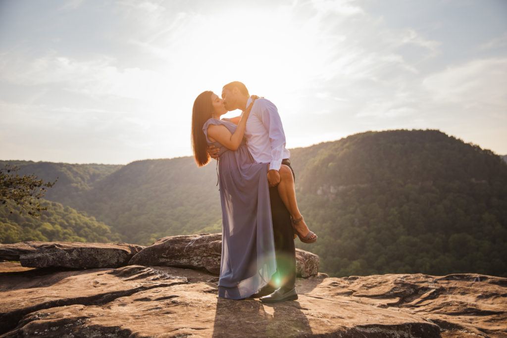 couple kissing during Fall Creek Falls engagement session, woman wearing long blue dress and man wearing dress shirt and pants