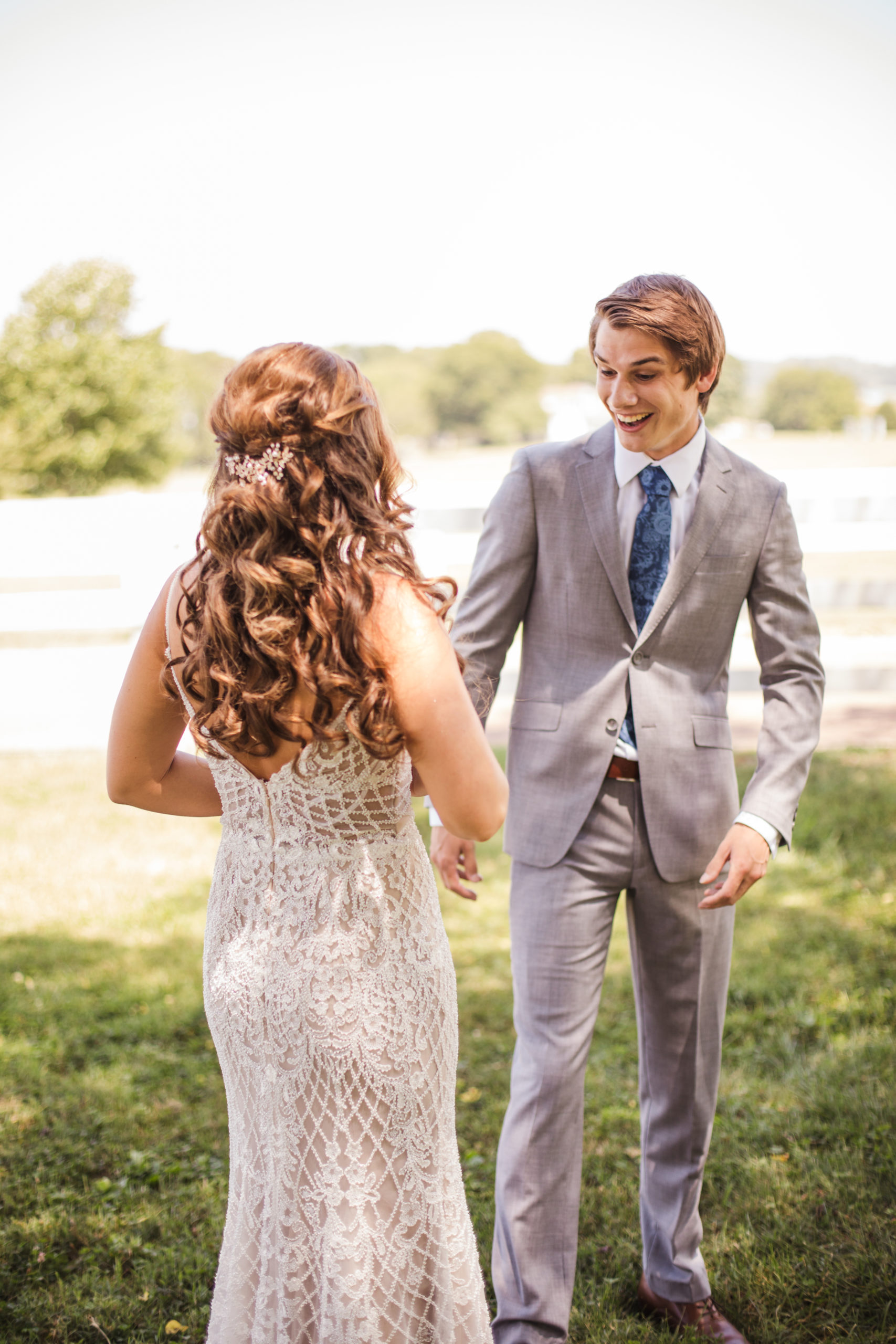 groom smiling at bride on wedding day while seeing her for the first time