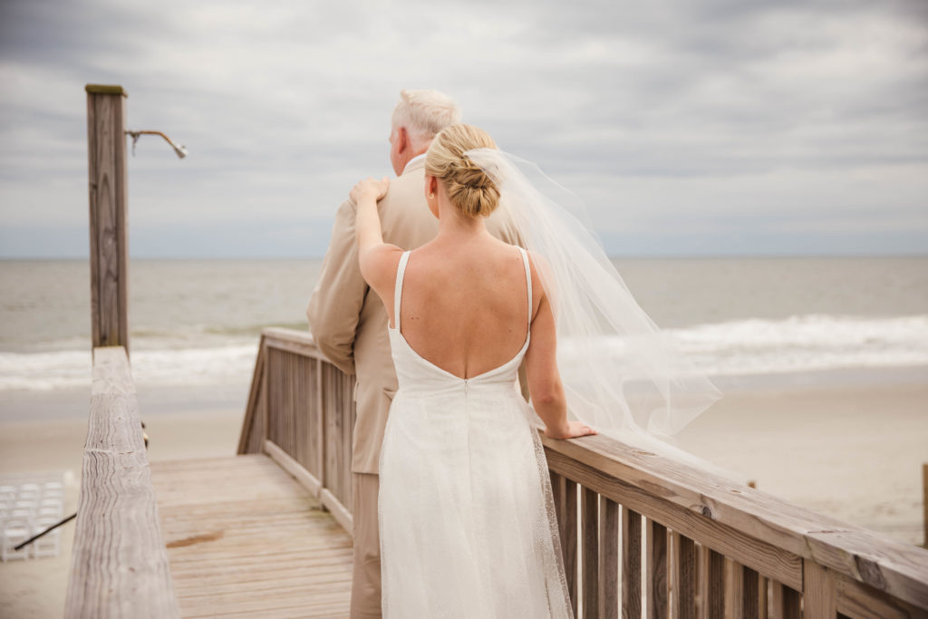 daughter walking down to beach to see dad on wedding day