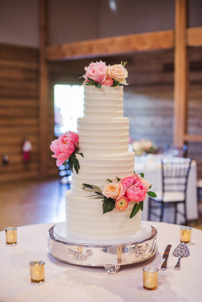 four tier classic white wedding cake with pink roses throughout