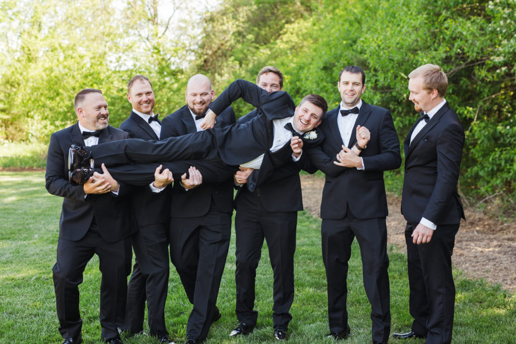groom being held by groomsmen at barn at sycamore farms wedding