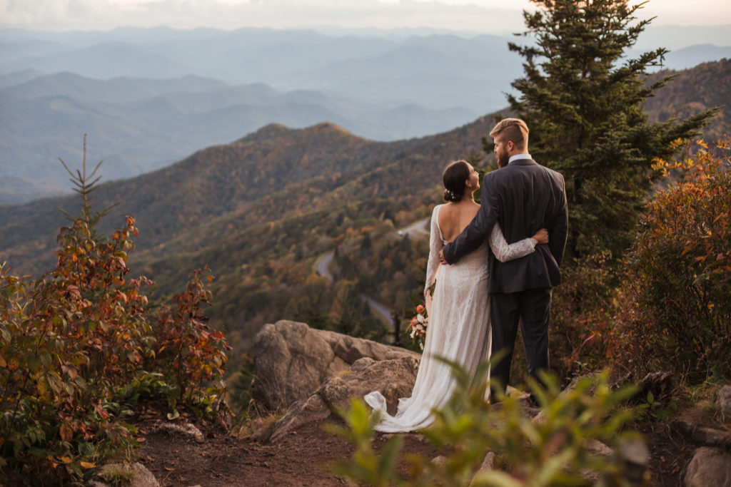 bride and groom hugging overlooking smoky mountain range