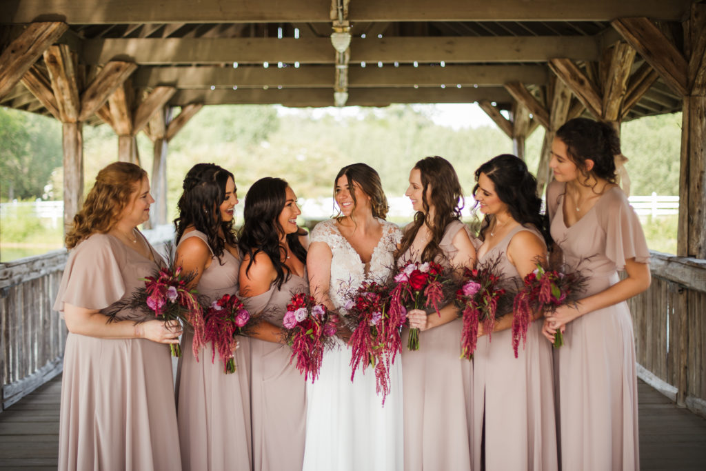 bride and bridesmaids wearing pink dresses holding stunning purple bouquets at wedding during bridals