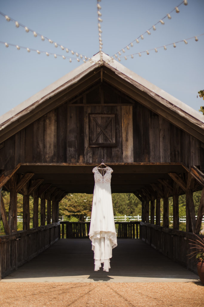 wedding dress hanging from old wooden barn for tombstone wedding at legacy farm detail shots