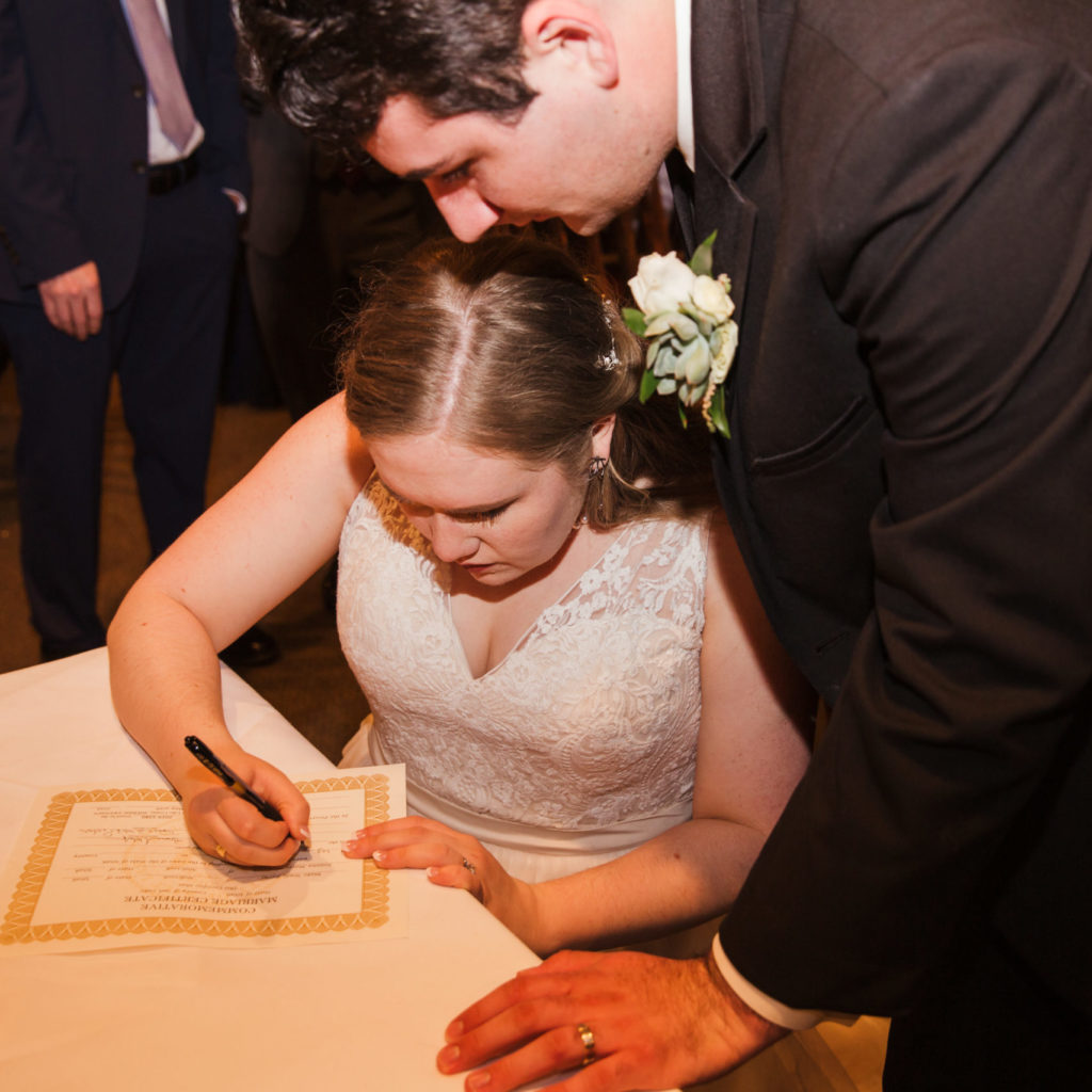 bride and broom signing marriage license