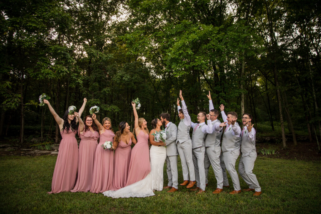 Bridal party cheering while the bride and groom kiss